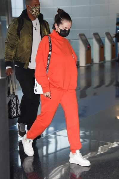 Selena Gomez Wears Statement Orange Sweats and Miu Miu Sneakers at JFK Airport