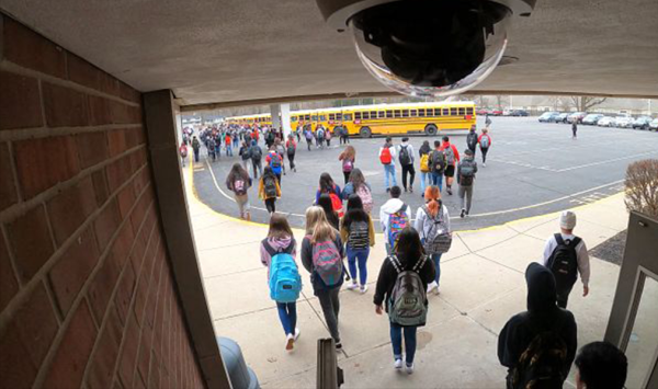 Students are monitored by a camera as they leave a school building.